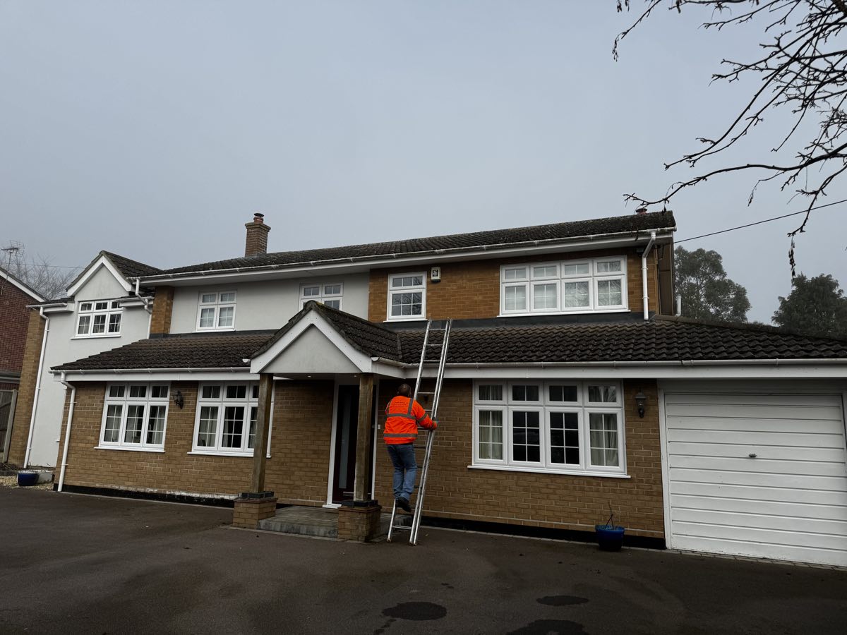 AC Guttering engineer cleaning the gutters on a large detached house