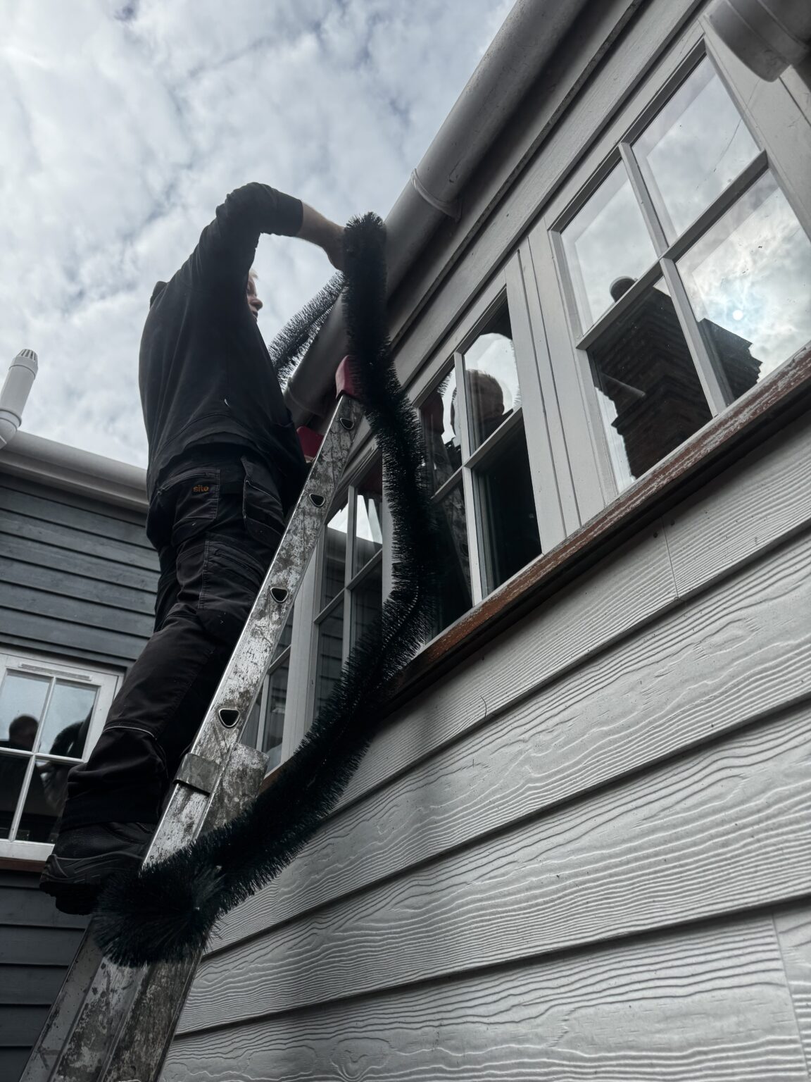 Engineer fitting gutter brush protection to a property